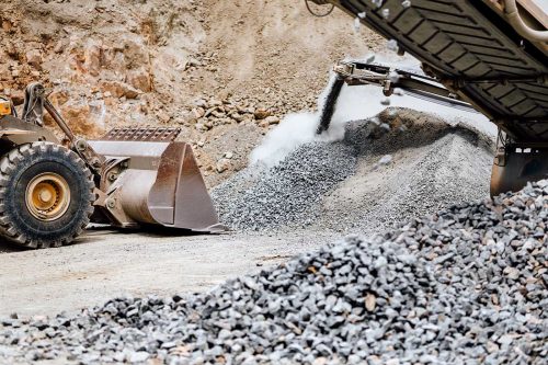 Wheel loader machine loading rocks in the open mine, iron ore mining details.